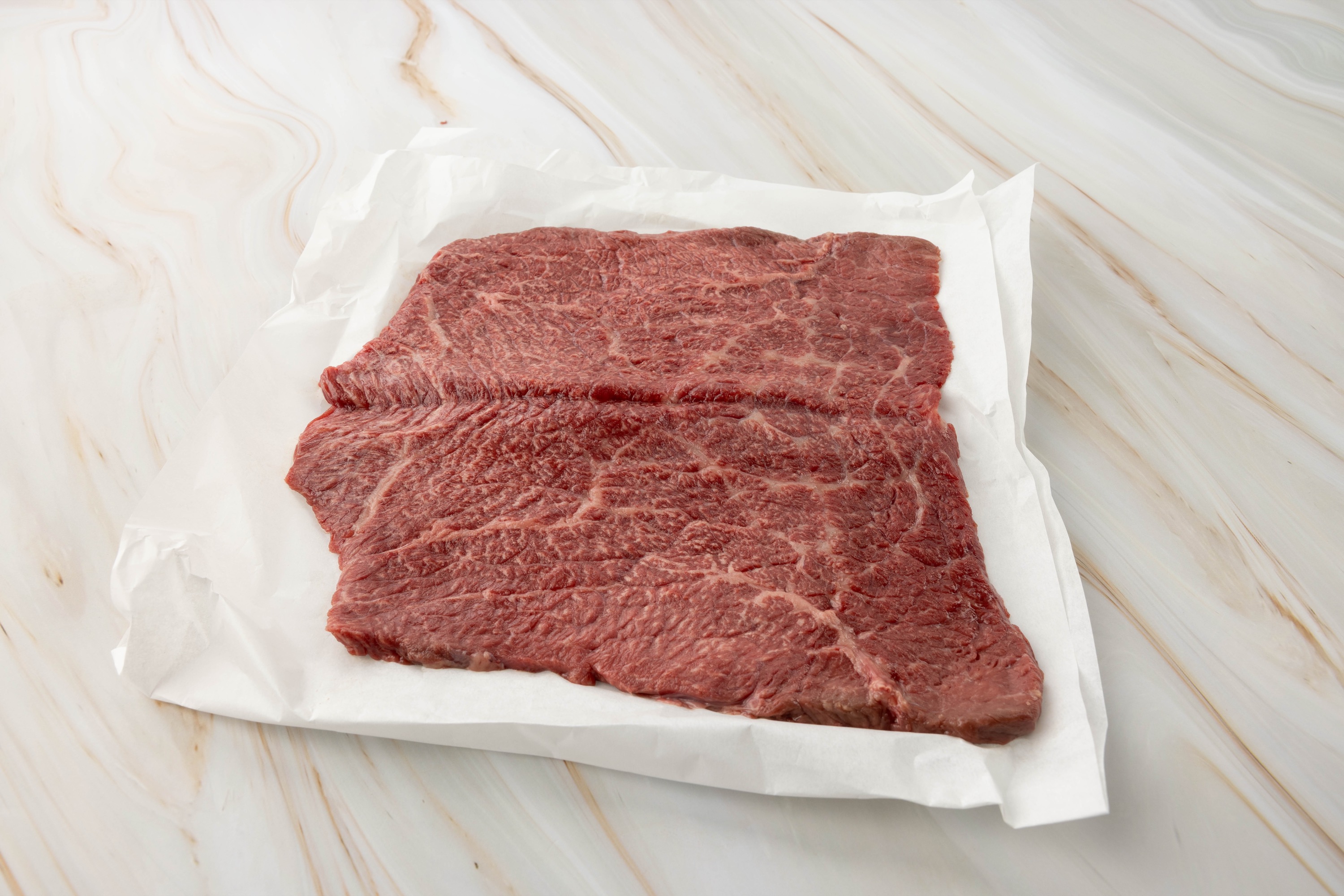 Rohes Fleisch auf weißem Papier, wagyu roulade