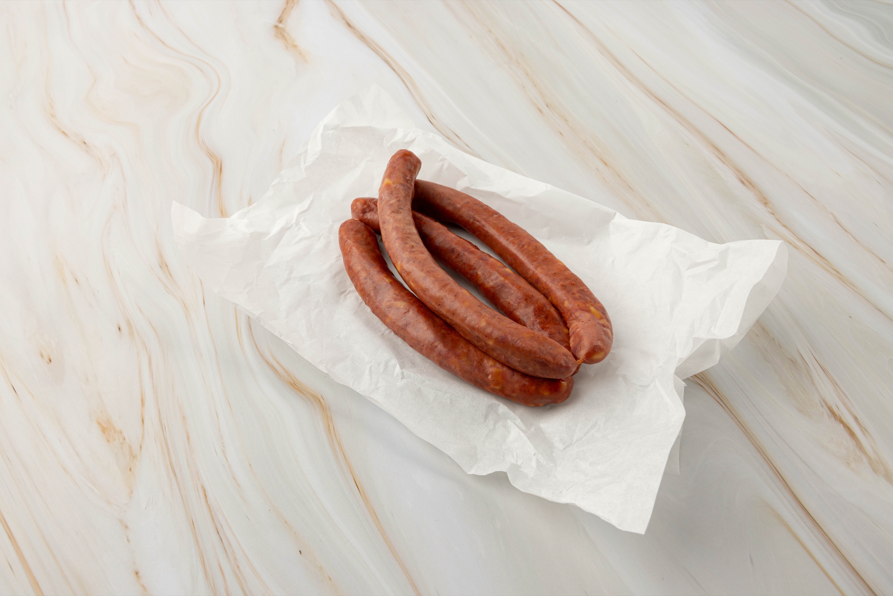 Rohwürste auf weißem Papier, wagyu käsekrainer