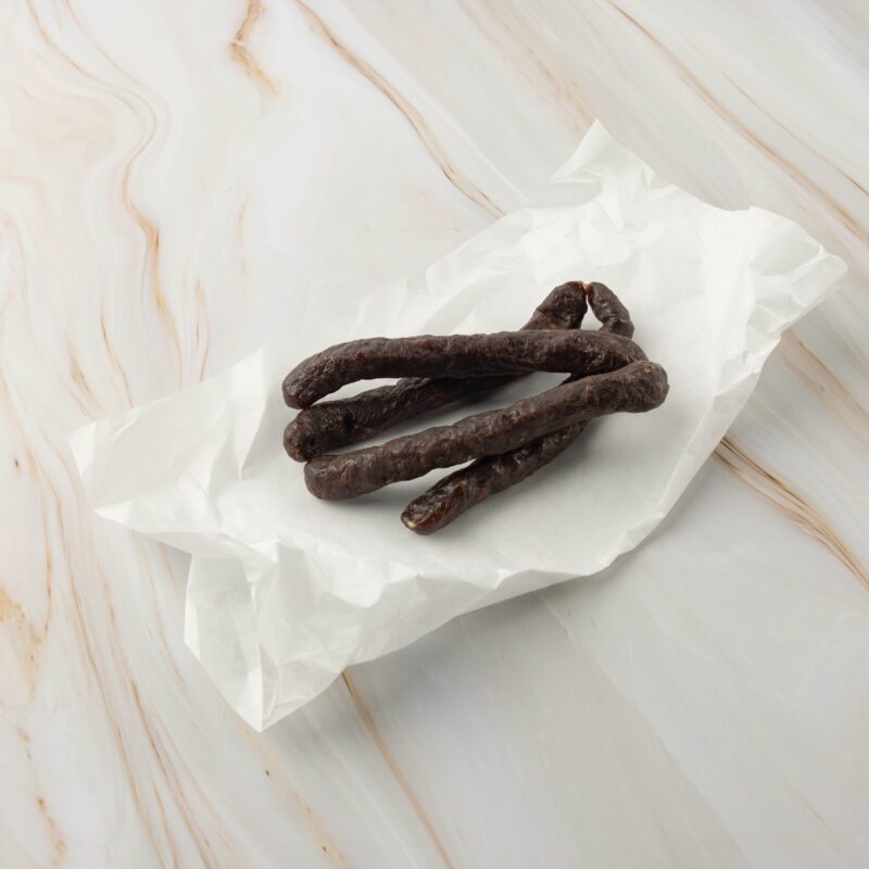 Dunkle, dünne Wurst auf Papier