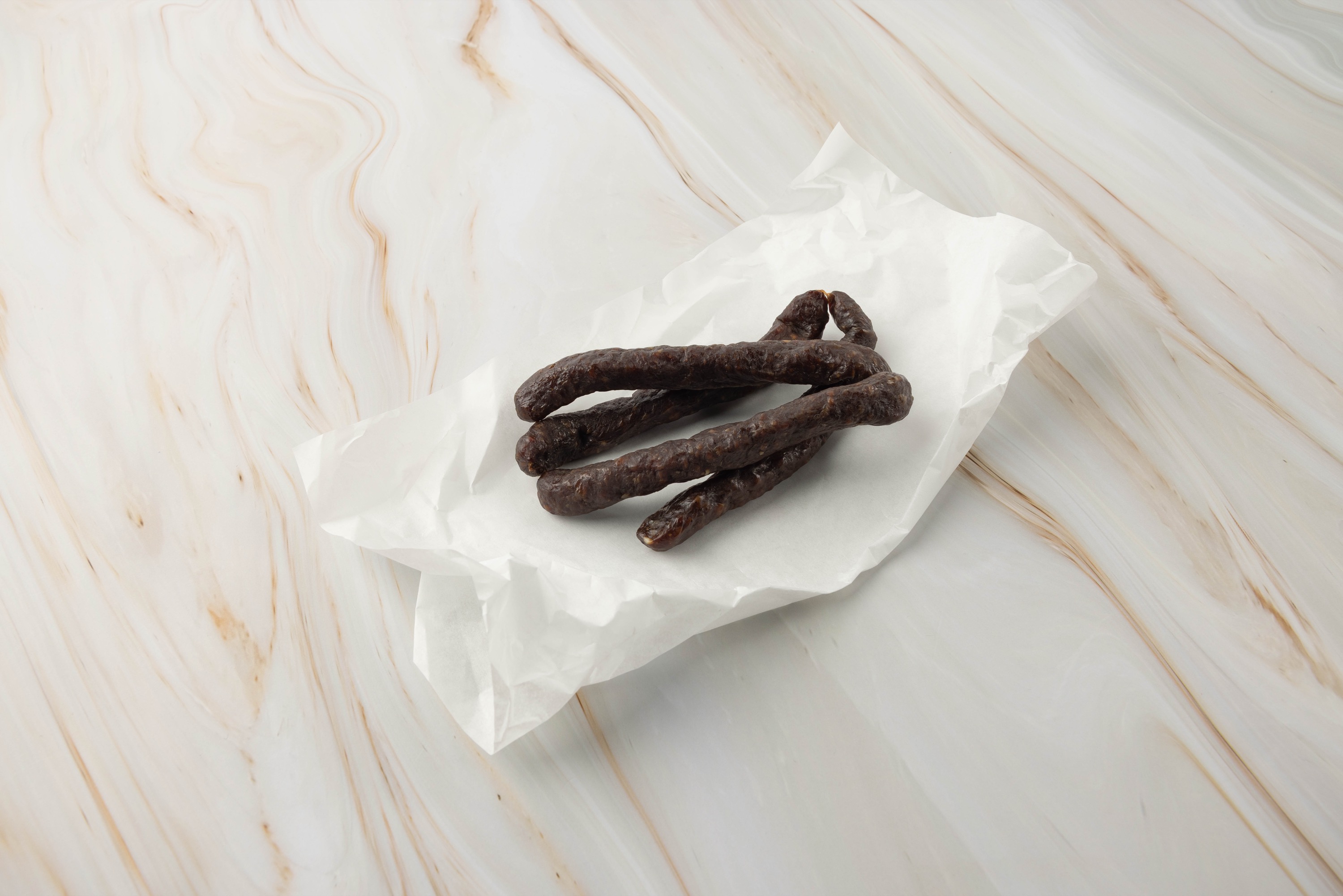 Dunkle, dünne Wurst auf Papier