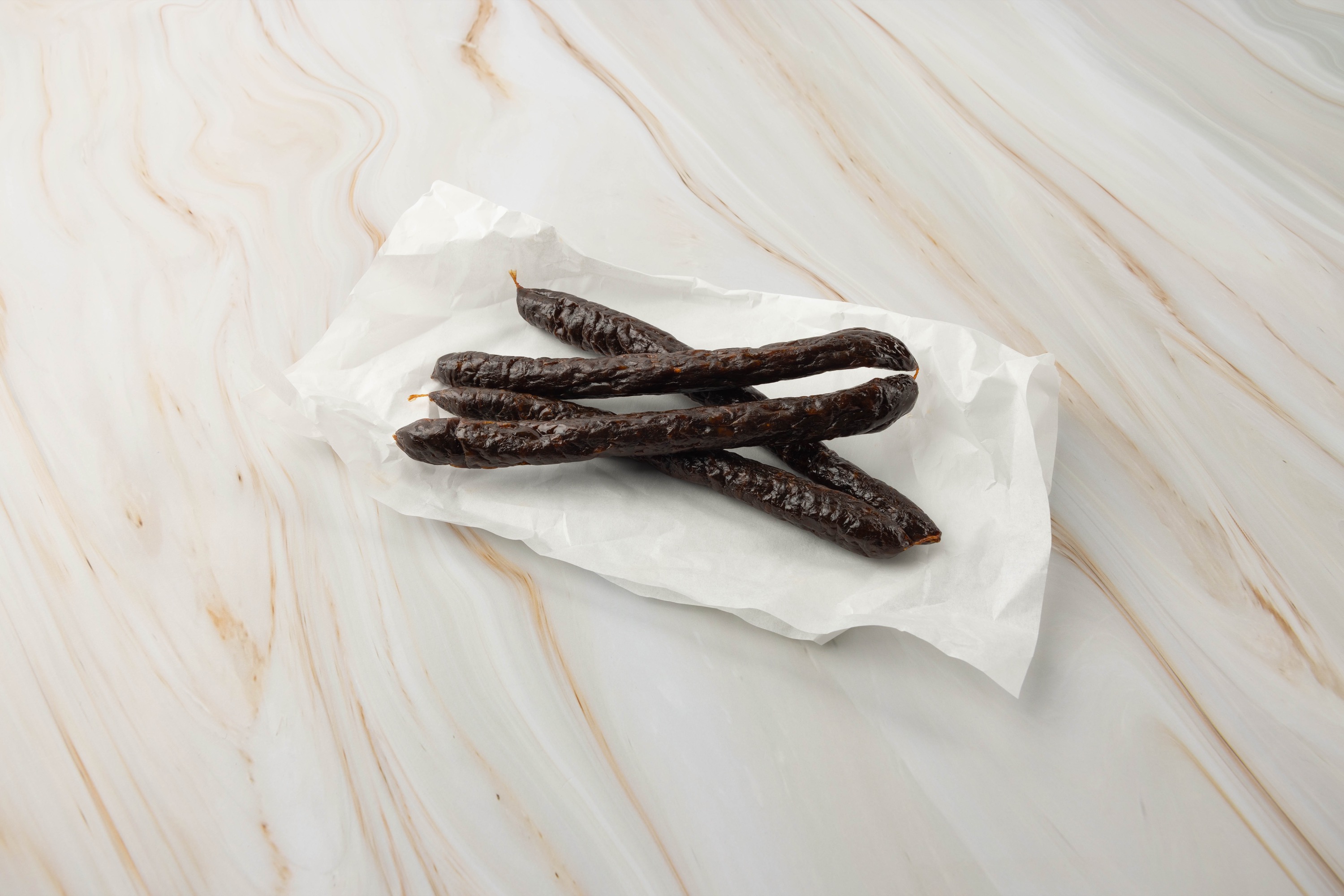 Dunkle Wurst auf weißem Papier