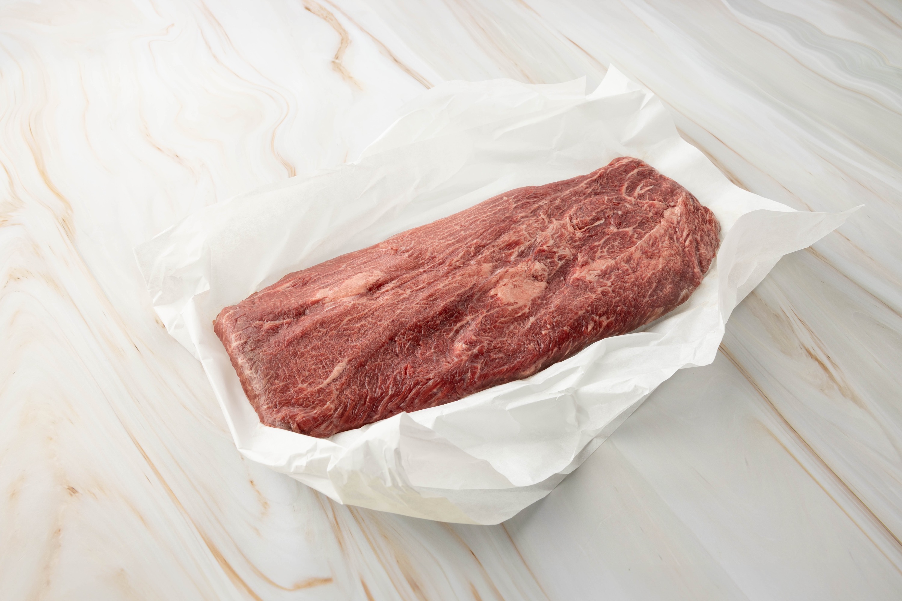 Rohes Fleisch auf weißem Papier, flat iron